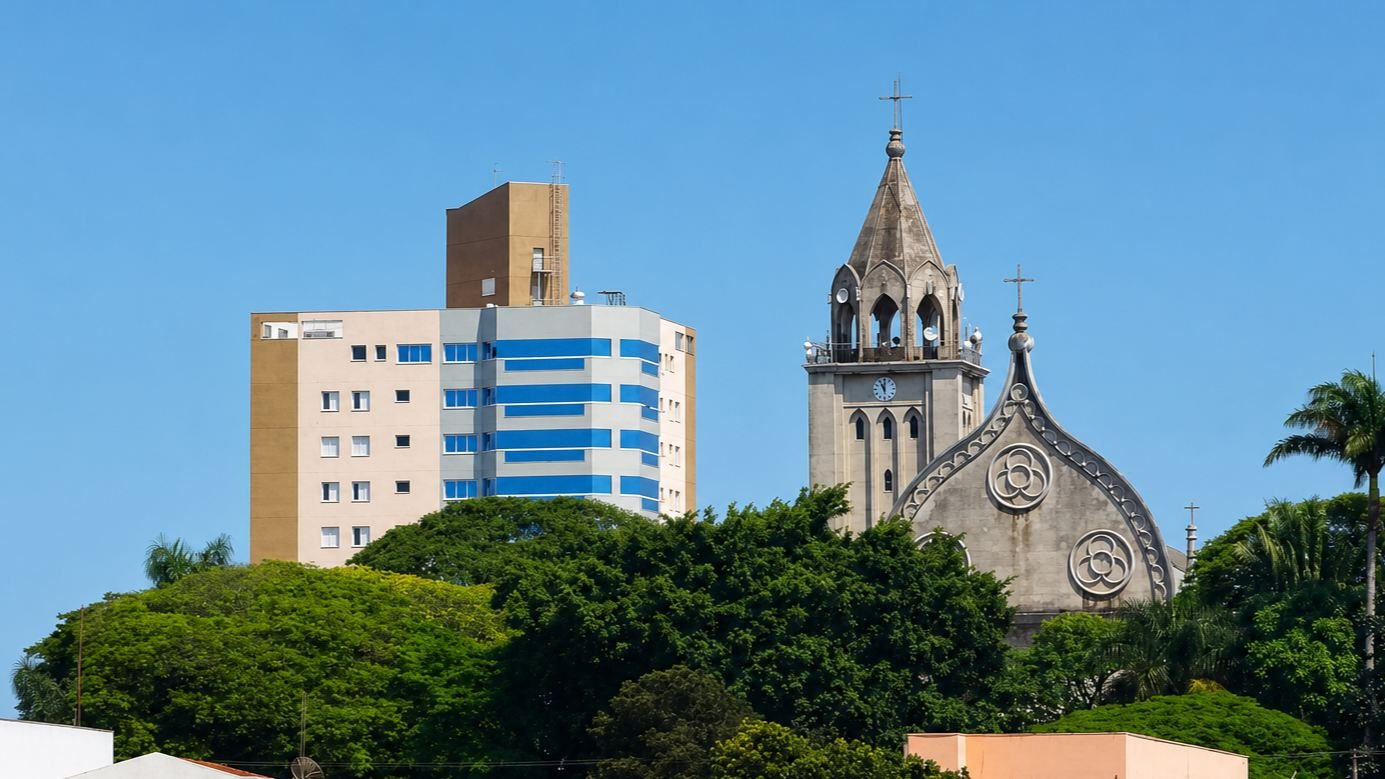 Igreja matriz e edifícios do centro de Taquarituba, cercados por vegetação